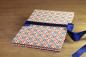 Preview: small photo album with geometric pattern in red, blue, white, blue satin bow